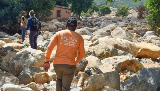 Back of man wearing long-sleeved orange t-shirt walking in rocky terrain