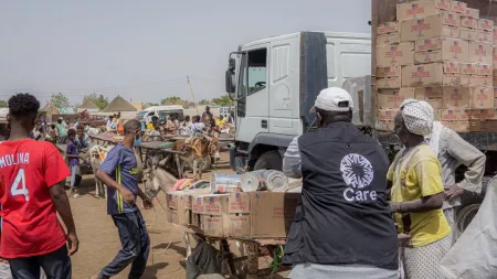 A food distribution scene in Kassala, Sudan, showing aid workers and locals gathering around a truck loaded with supplies, highlighting the hunger crisis in the country.
