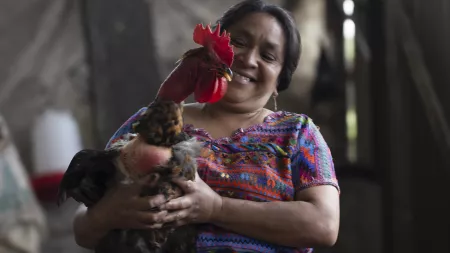 An agricultural producer holding one of her chickens