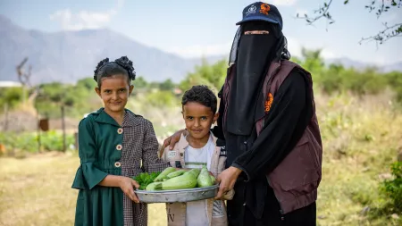 A woman and her children with vegetables that they harvested from their garden