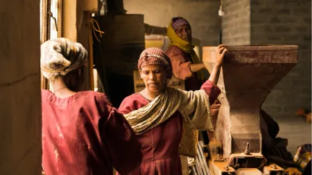 Women wearing red dresses working in food processing factory.