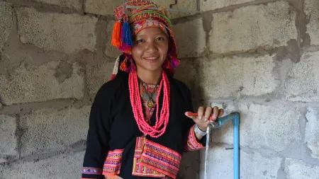 A woman in accesses clean water through a CARE-supported system, improving health and daily life.