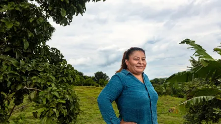 Woman standing sideways with hands on waist in a green area.