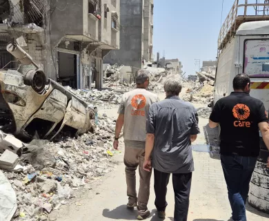 3 CARE staff walking amid rubble in Gaza