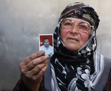 Woman  with glassed and a headscarf showing a photo of a man