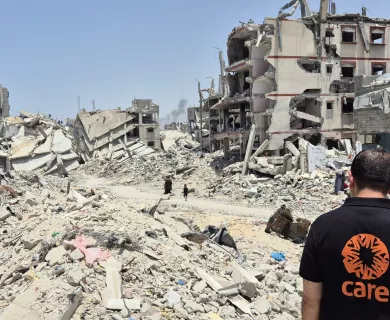 Back of Man wearing shirt with CARE's logo looking at rubble