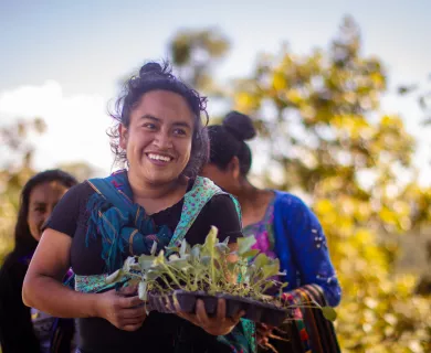 Woman wearing black t-shirt, smiling while carrying fresh plants 
