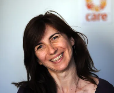 Portrait photo of woman with shoulder-length dark hair, head bent to the left, smiling at the camera.